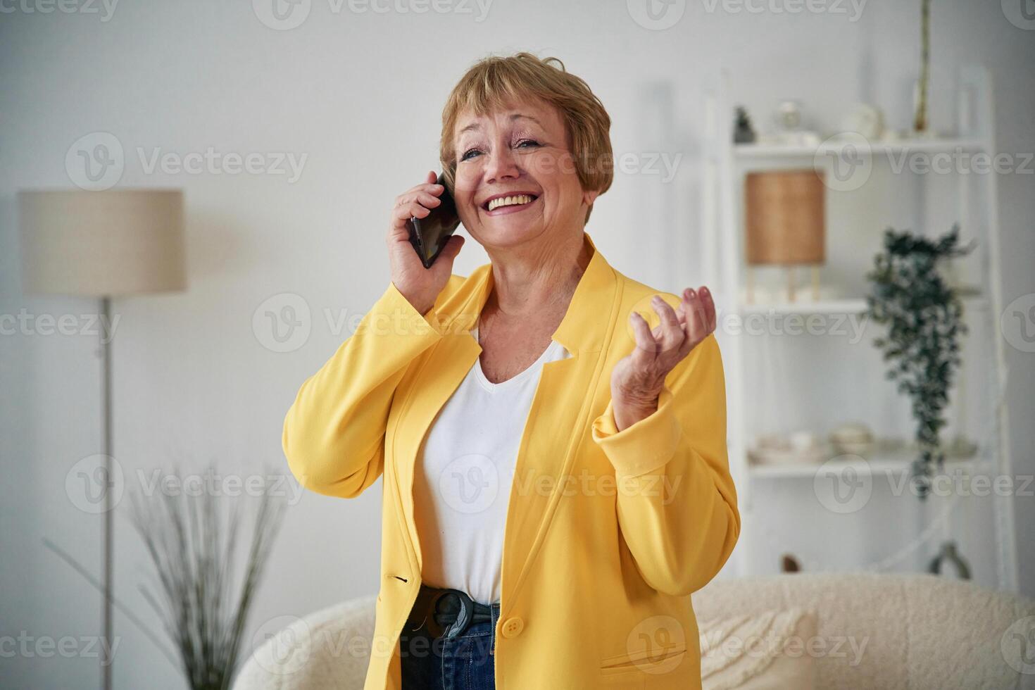 Talking, by phone. Senior elderly woman is at home in the living room photo