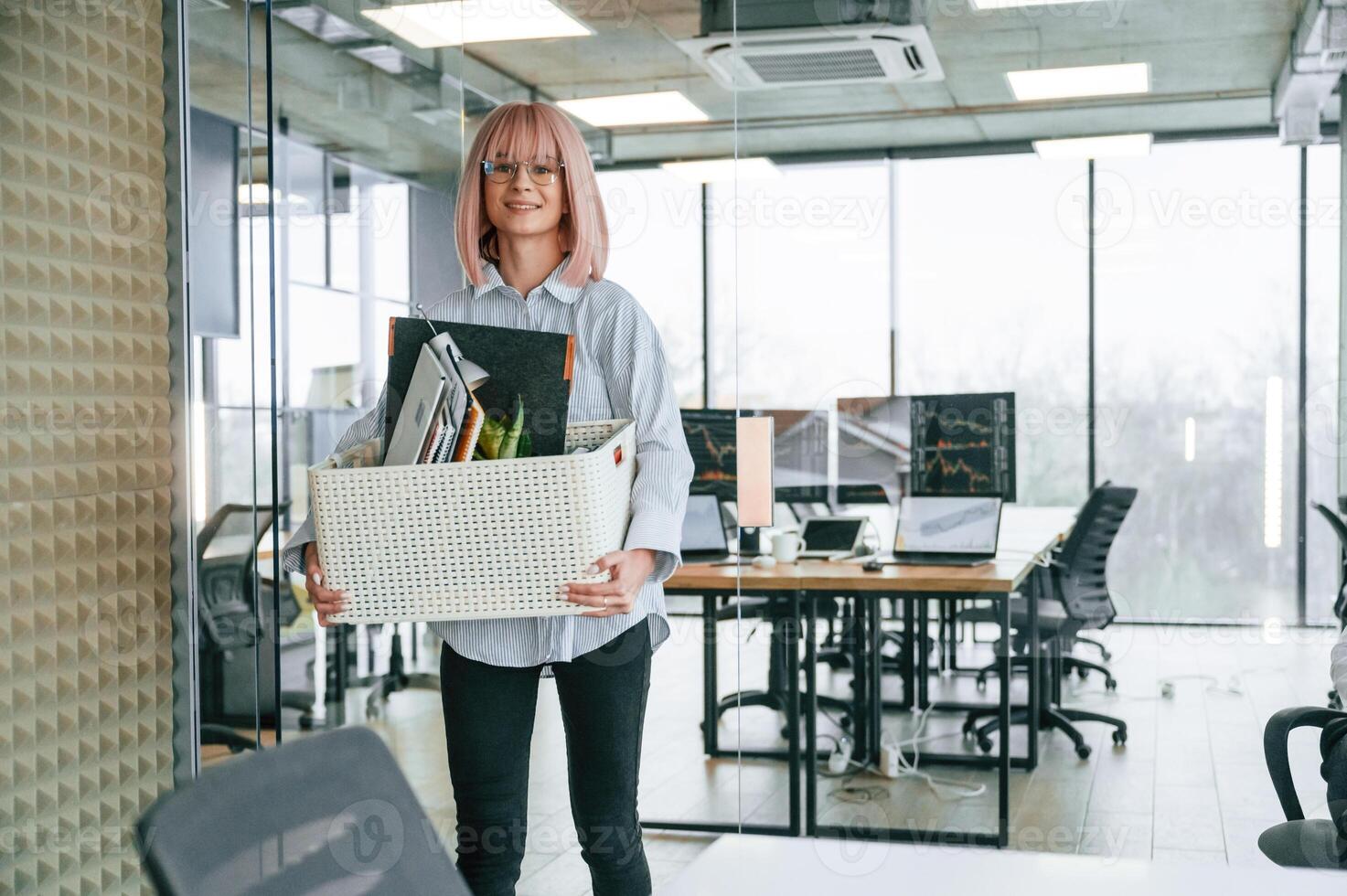 Standing ,and smiling... Unemployed ,woman with pink hair is with personal belongings after being fired photo