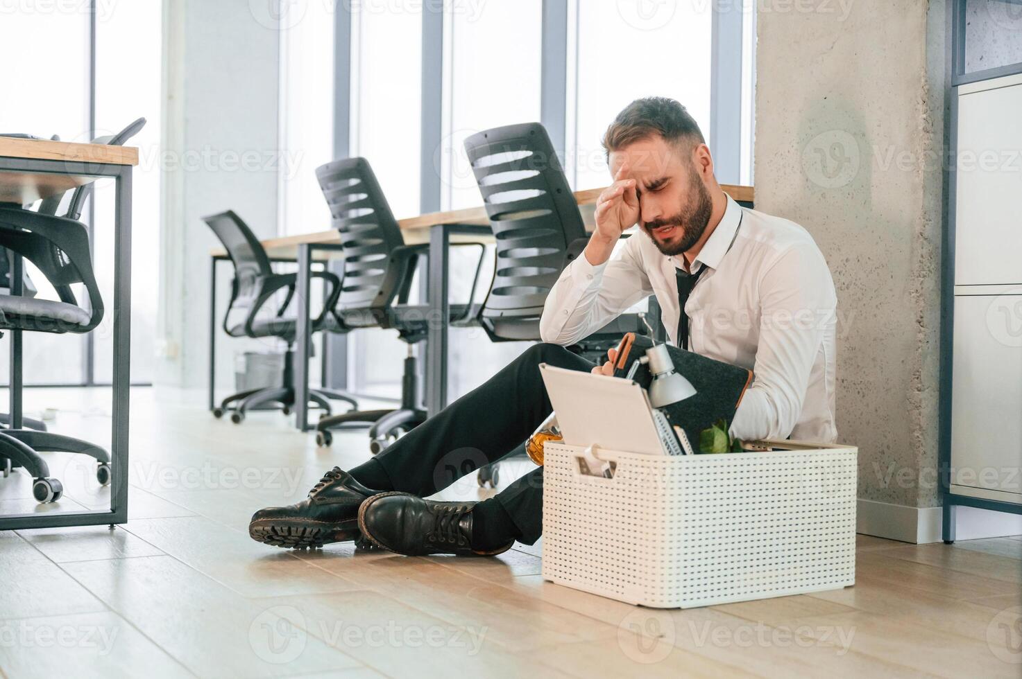 Depressed, sitting ,on, the floor.. Unemployed man is with personal belongings after being fired photo