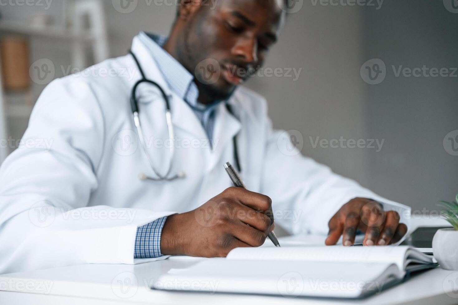 Filling in the document, writing, by, using pen. Black man as doctor in the clinic office photo