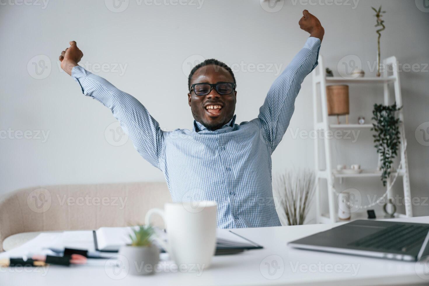 Celebrating success. With hands up.. Businessman is working in the office by laptop photo