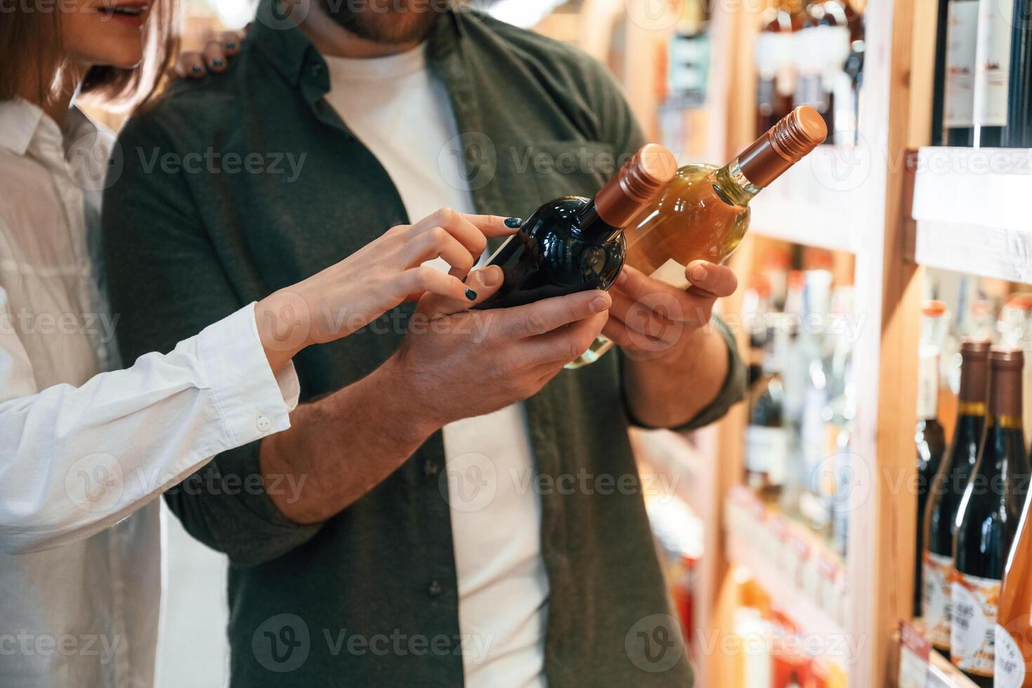 Choosing ,between, two different bottles. Man and woman in the wine shop photo