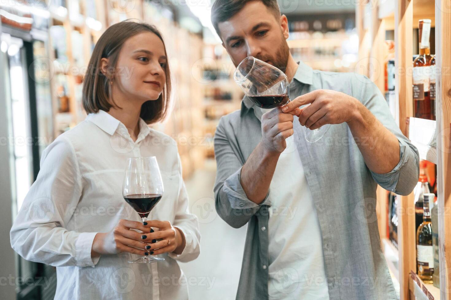 Glasses with ,drink.. Take a sample. Man and woman are choosing wine in the shop photo