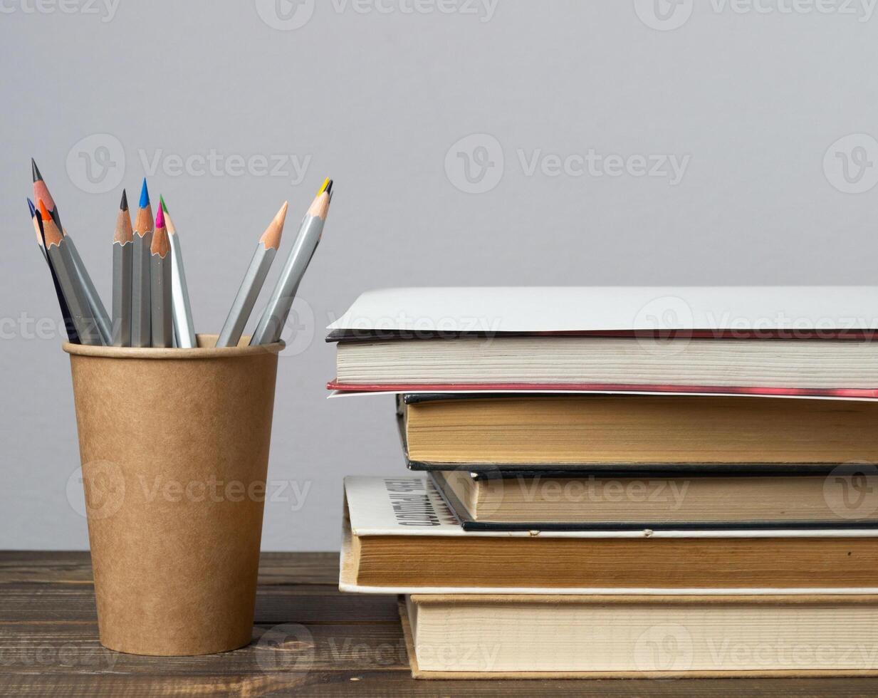 Stack of books and a pencil holder on a table photo