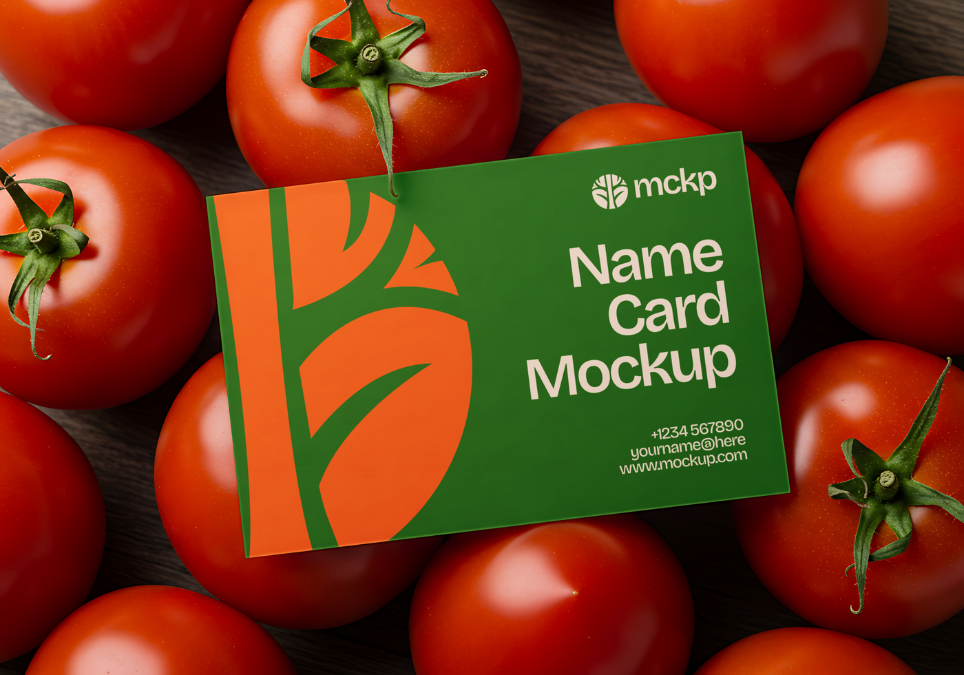 A green name card mockup rests amongst a pile of ripe red tomatoes psd