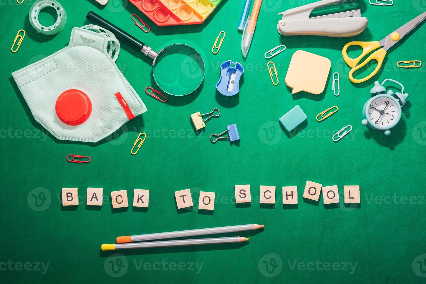 Back to school is written on a green background with various school supplies suc photo