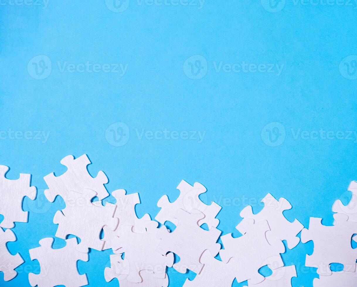 Blue background with a pile of white jigsaw puzzle pieces photo