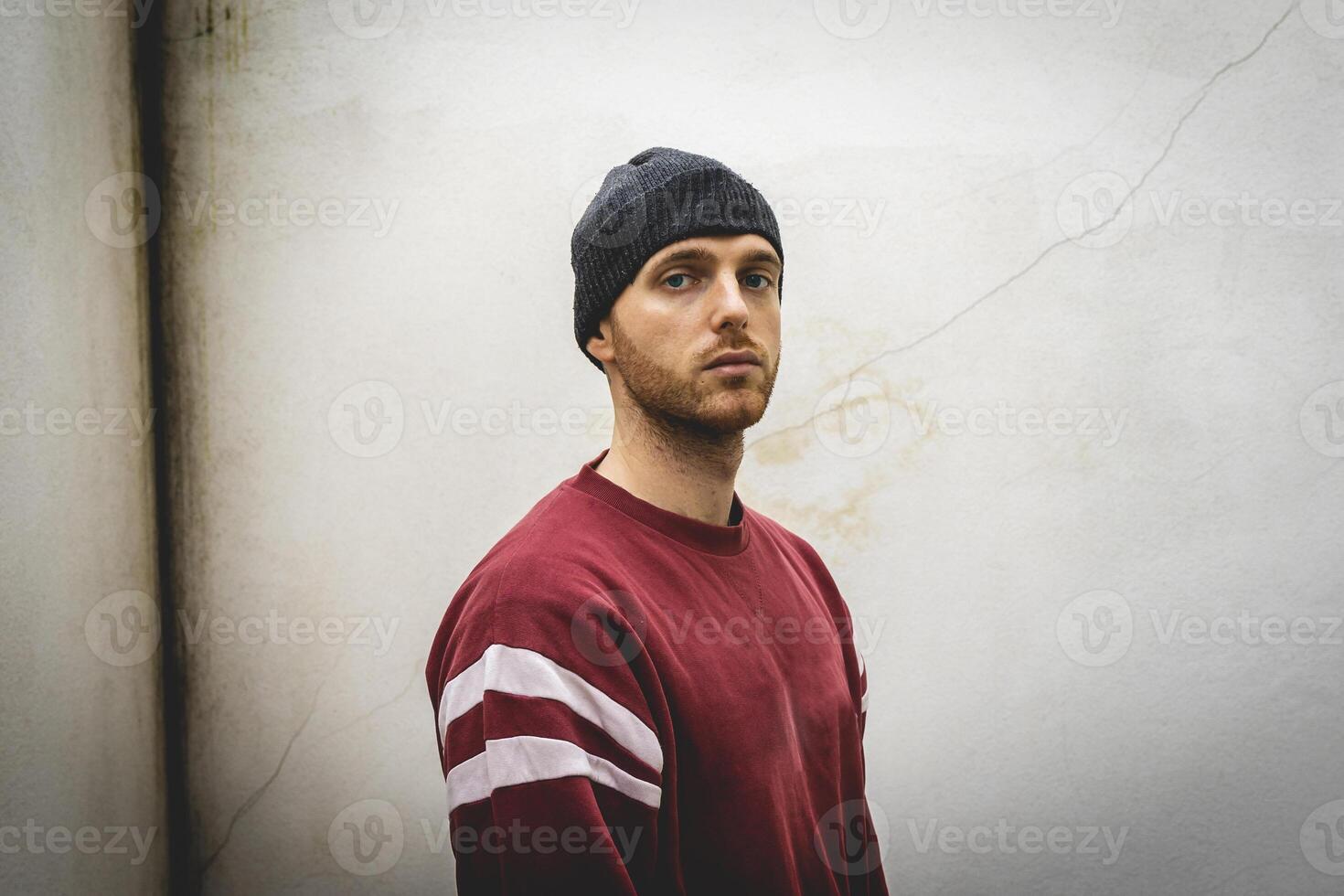 portrait of young rapper posing in front of a white wall photo