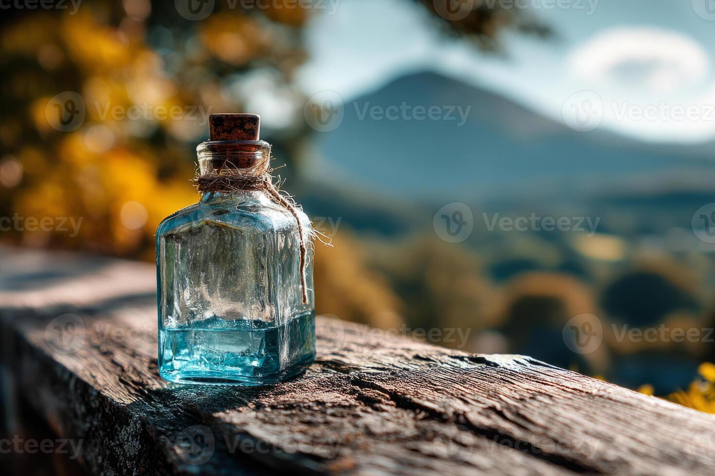 Glass bottle with cork on rustic wood surface in mountain valley photo