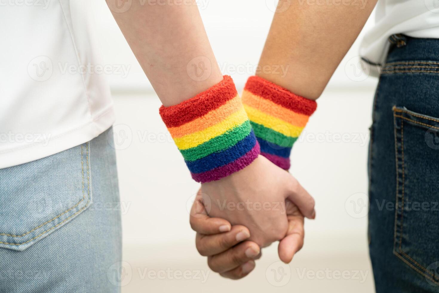 Asian LGBT couple woman holding hand wearing rainbow wristband. photo
