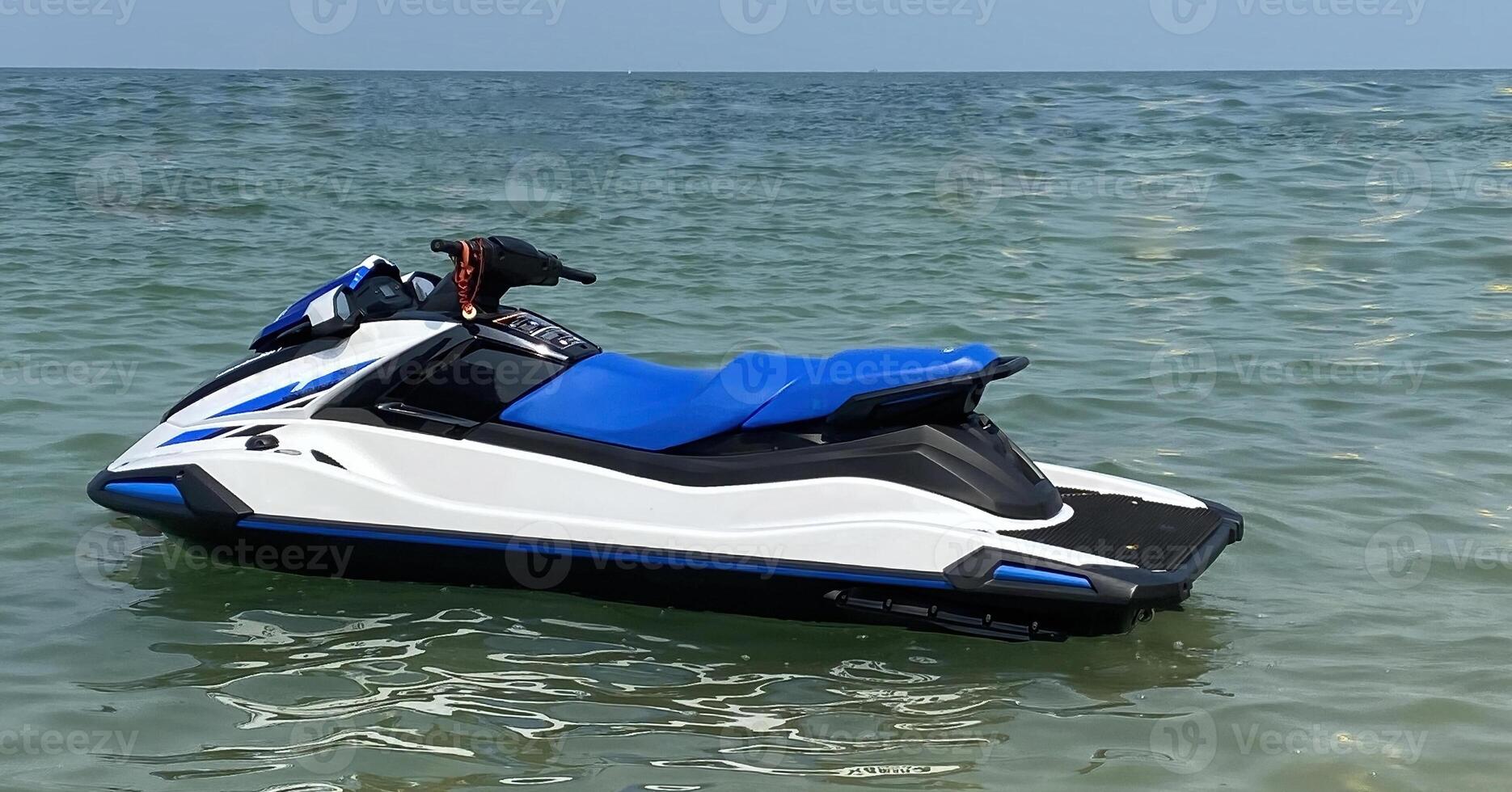 A jet ski sits still on the sea with no one riding it. It is used for water and marine sports designed for high speed competitions and traveling over water. photo