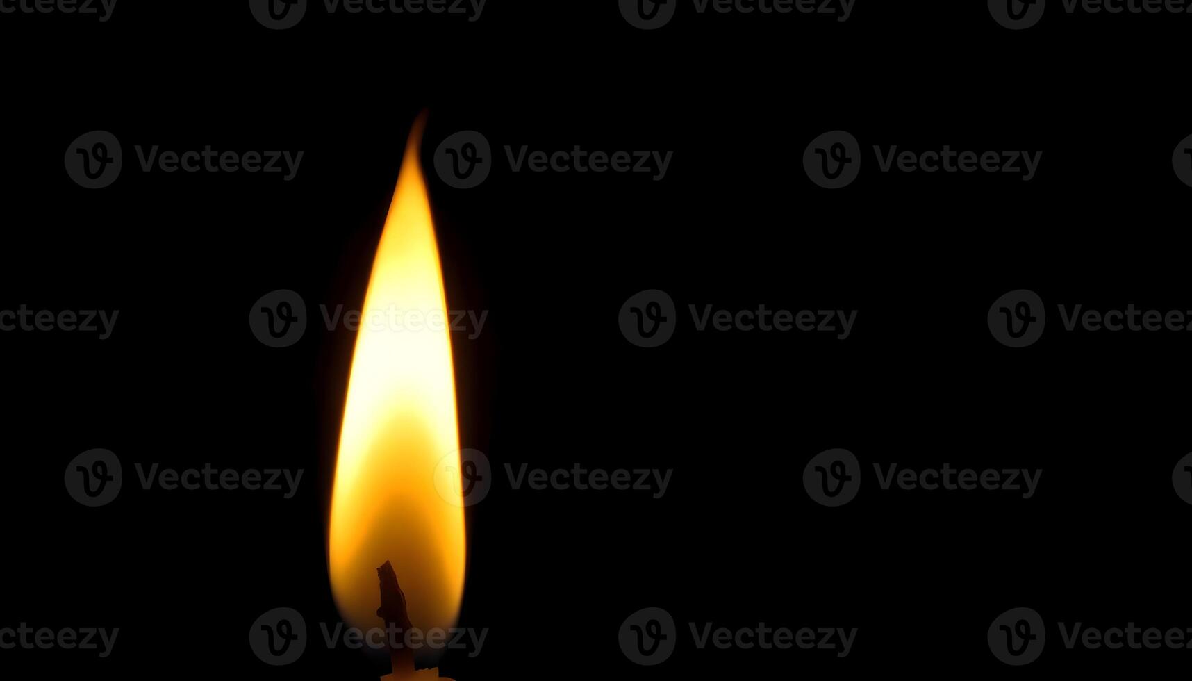 A single candle is lit in the dark photo