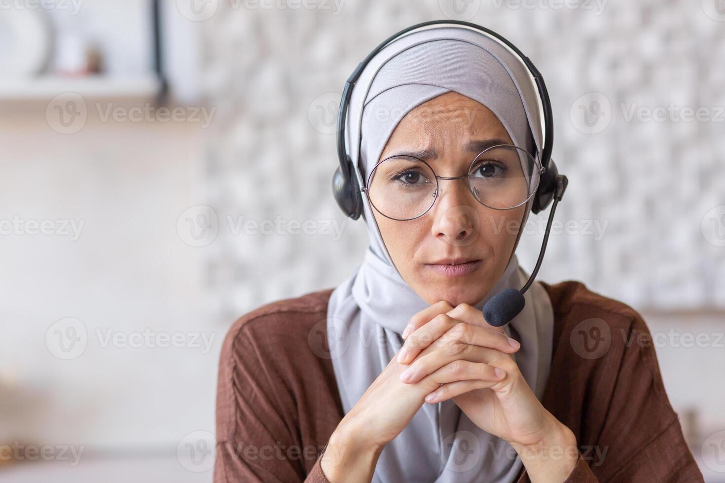 Close-up photo. Portrait of young Arab woman in hijab and headset. He looks seriously into the camera. photo
