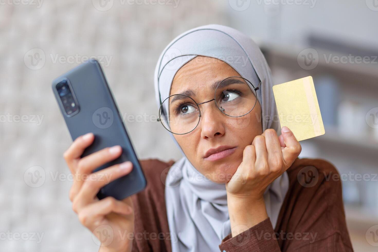 Upset and deceived woman at home received an error and wrong code, Muslim woman in hijab trying to make a purchase in an online store and transfer money online sitting at home in the kitchen. photo