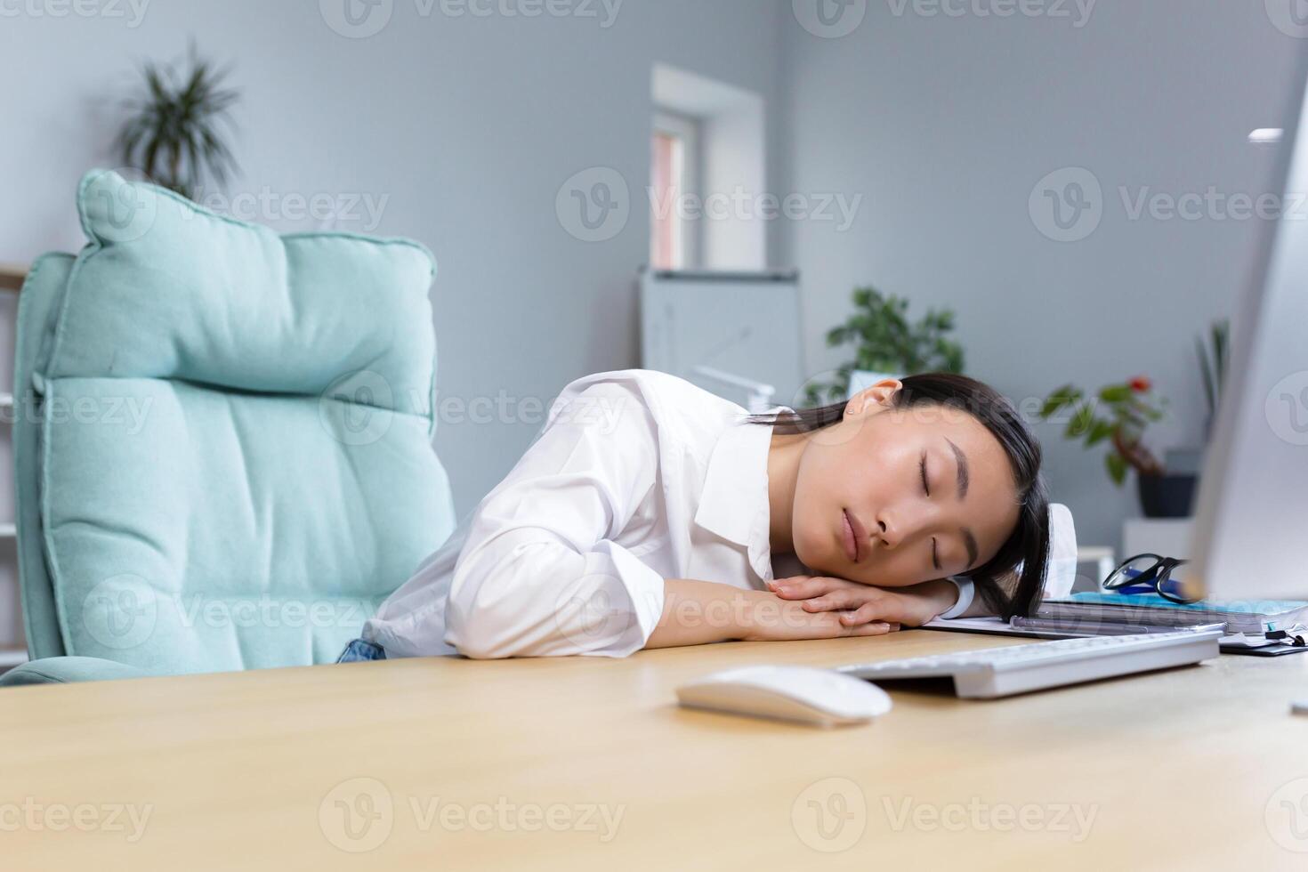 Young Asian businesswoman fell asleep at the desk on her hands in the office, tired, routine, boring work, needs a break. photo