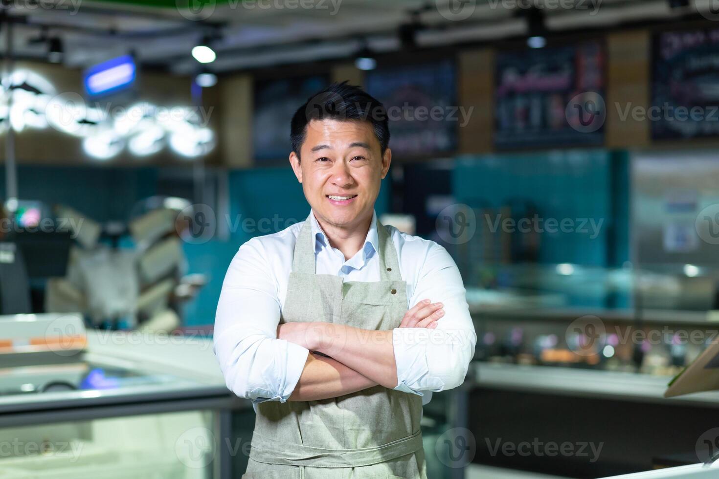 Portrait of Asian salesman in seafood and fish shop man smiling with arms crossed and looking at camera photo