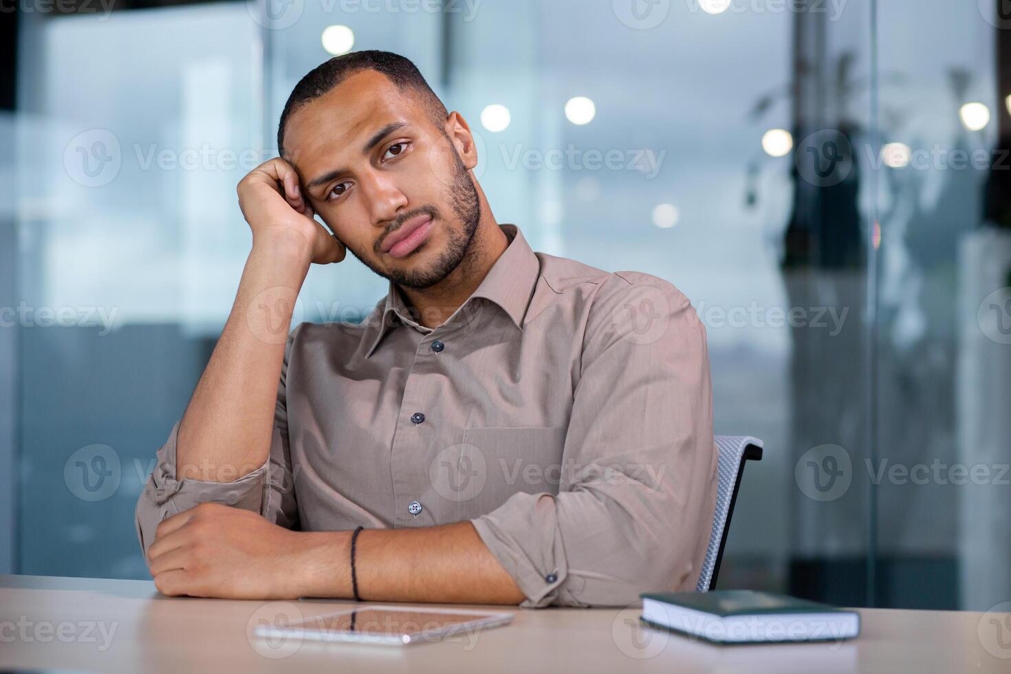 Upset disappointed and sad looking at web camera, man unhappy on online meeting sitting at table inside office at workplace. photo