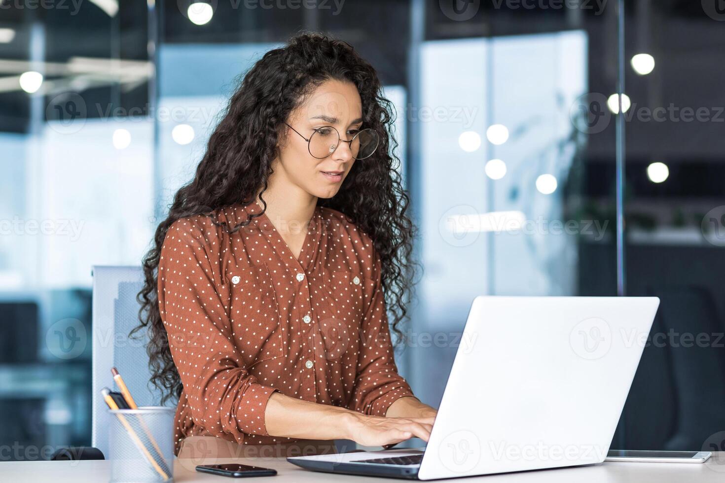Beautiful indian woman programmer web developer focused and confident working on laptop writing code programming business woman worker in modern office working in casual clothes. photo