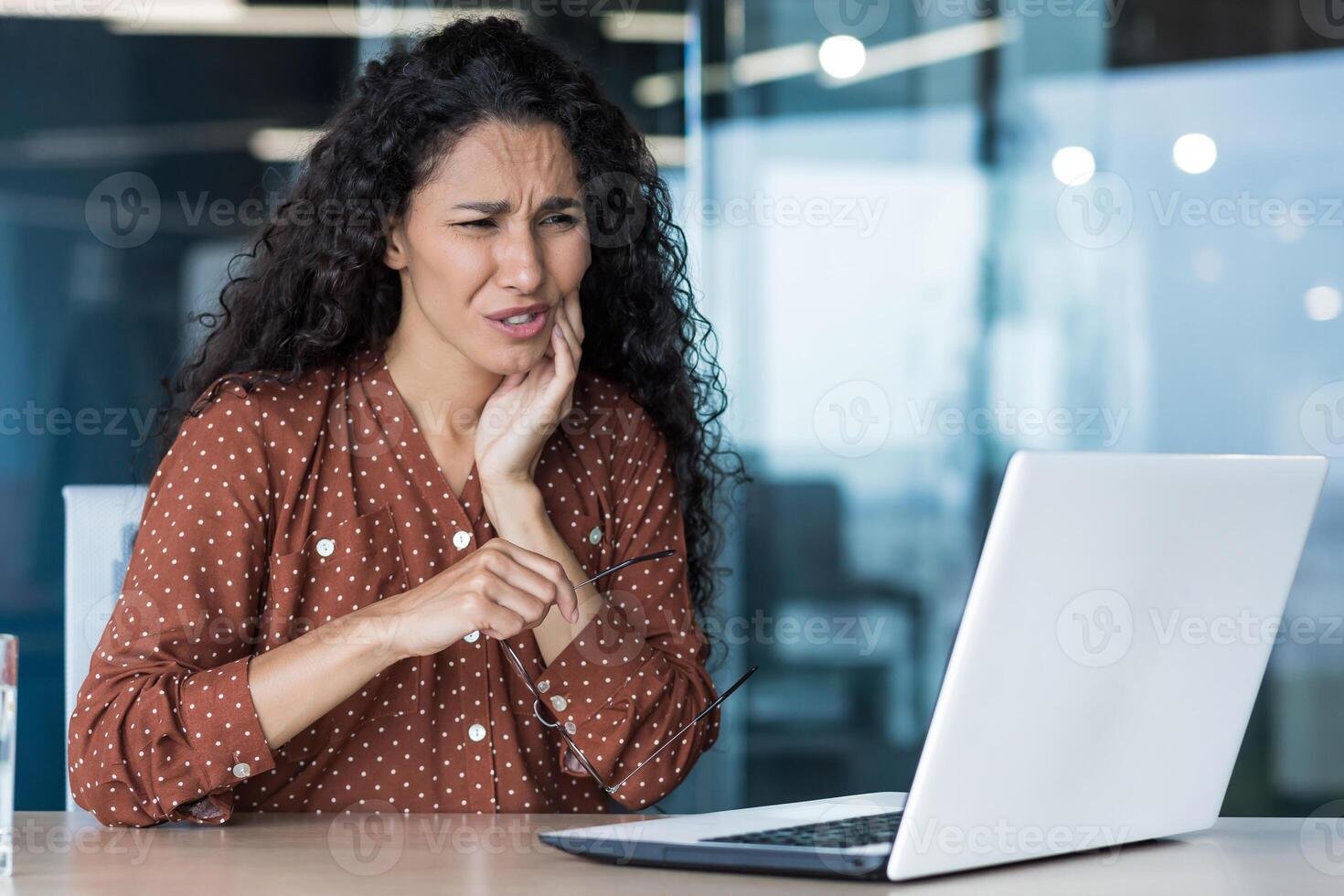 Beautiful business woman working inside office building, patient has severe toothache, worker uses laptop photo