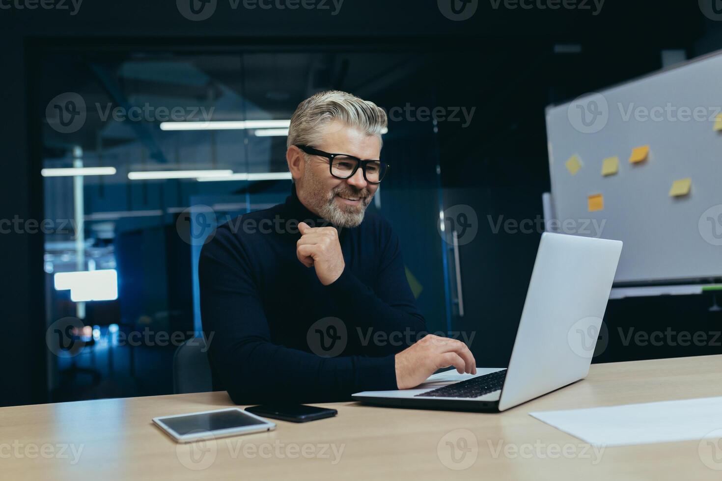 Mature successful boss working inside modern office, senior gray haired businessman at work working with laptop smiling and happy investor happy with achievement. photo