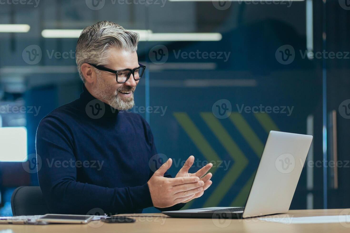 senior mature gray-haired man using laptop remote communication business meeting experienced businessman in glasses working modern office investor smiling talking colleagues. photo