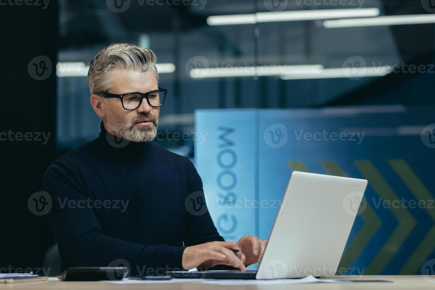 Thinking man inside office at work, mature adult businessman looking at laptop screen, gray haired boss reading and analyzing financial data, employee making decision. photo