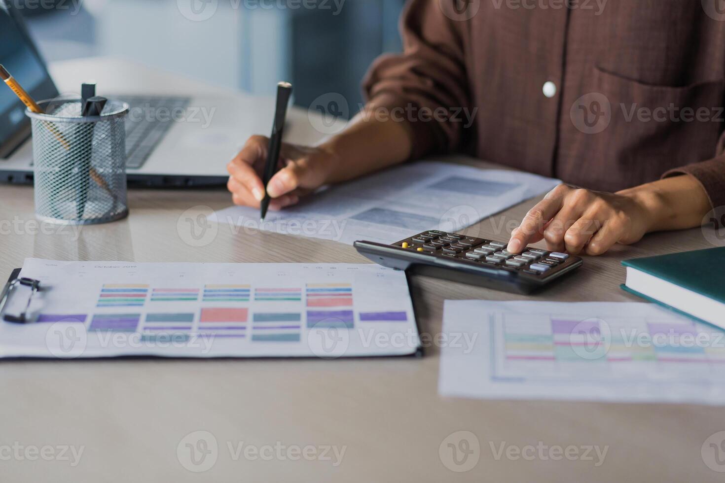 Close-up photo of a business woman's hand at work, selected focus, a female accountant calculates on a calculator and signs financial reports and documents