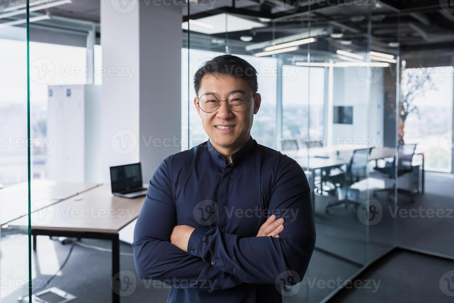 Portrait of successful and experienced mature asian businessman, man working inside modern office, smiling and looking at camera with crossed arms, director investor in glasses and shirt. photo