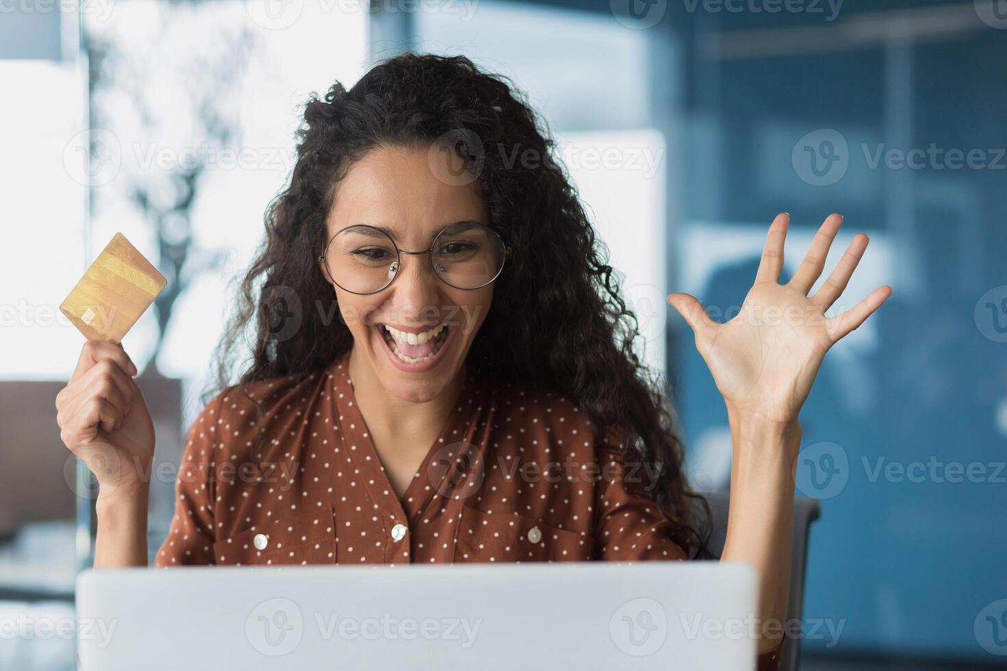 Close-up photo portrait of happy shocked woman, buyer holding bank credit card in hands, business woman looking satisfied in laptop, successful purchase in online internet store