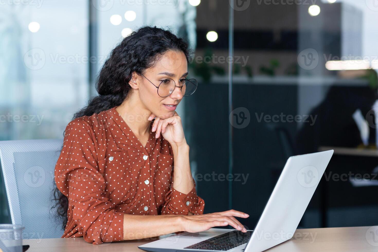 Successful Indian woman developer programmer working inside modern office, using laptop at work to write program software code, smiling and happy startup. photo