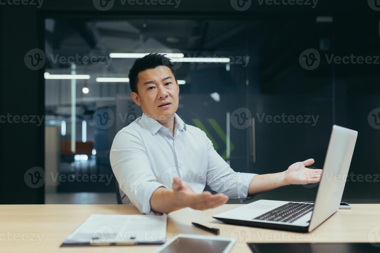 Portrait of Asian businessman man, disappointedly spreading hands and looking at camera, Korean owner manager working in modern office, not satisfied with work result. photo
