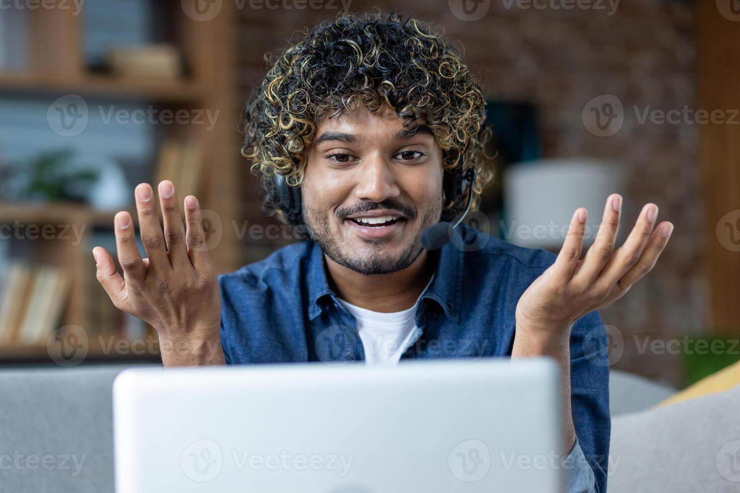 Man working from home remotely, sitting on sofa in living room, freelancer businessman using headset phone and laptop for call, online meeting and remote conference photo