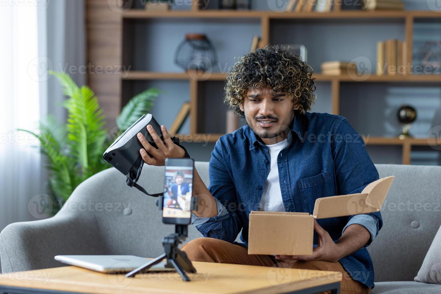 Man writes negative review about product purchased in online store. Influencer blogger sits at home on sofa in living room, uses tripod and phone to record online stream photo