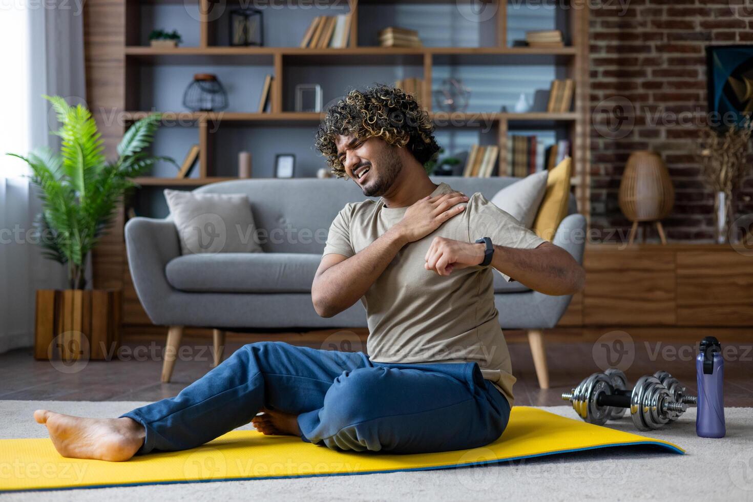 A man was injured while doing fitness and active sports exercises while sitting on the floor in the living room at home, pain in the shoulder joint photo
