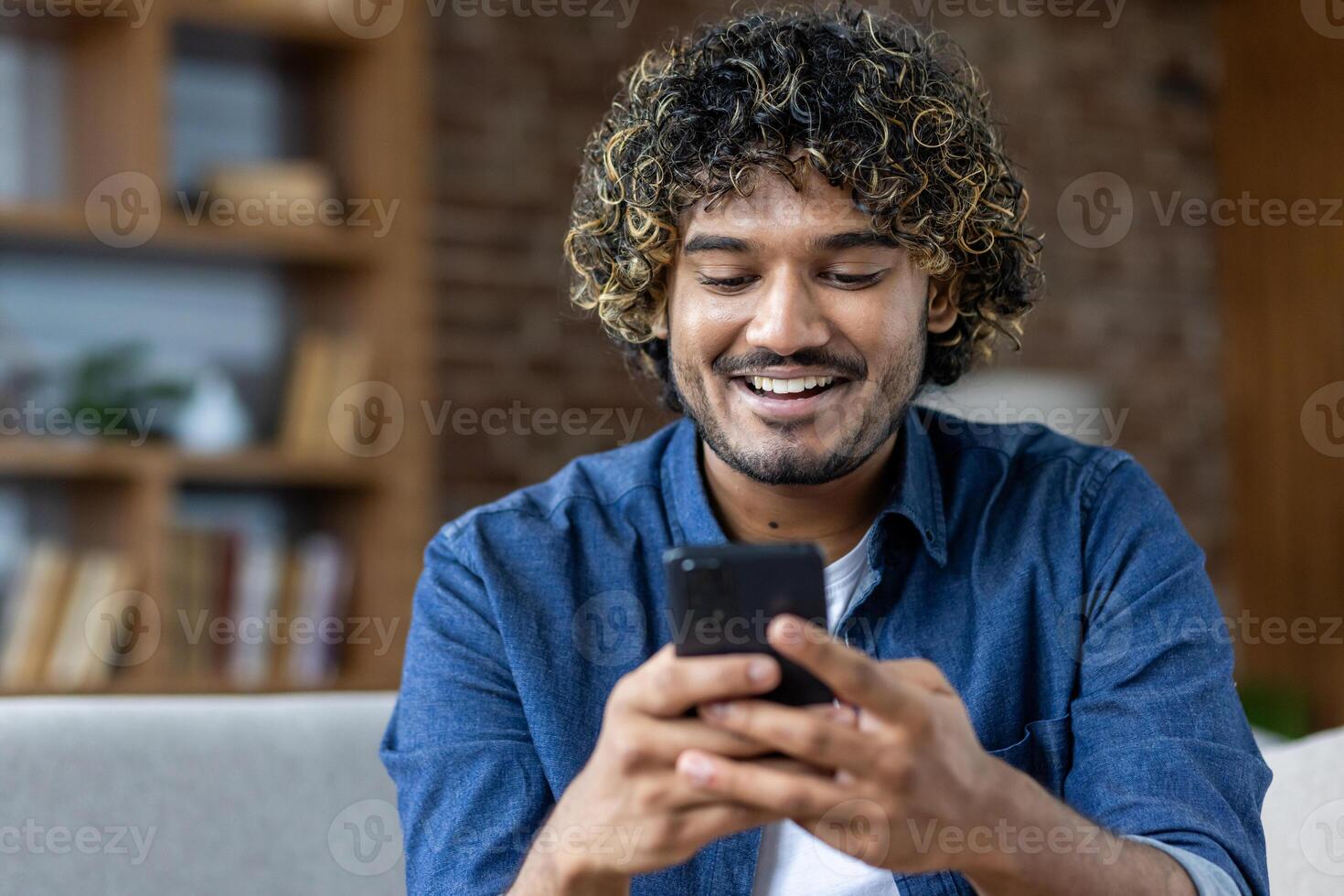 Man smiling and engaging with his smartphone in a cozy living room photo