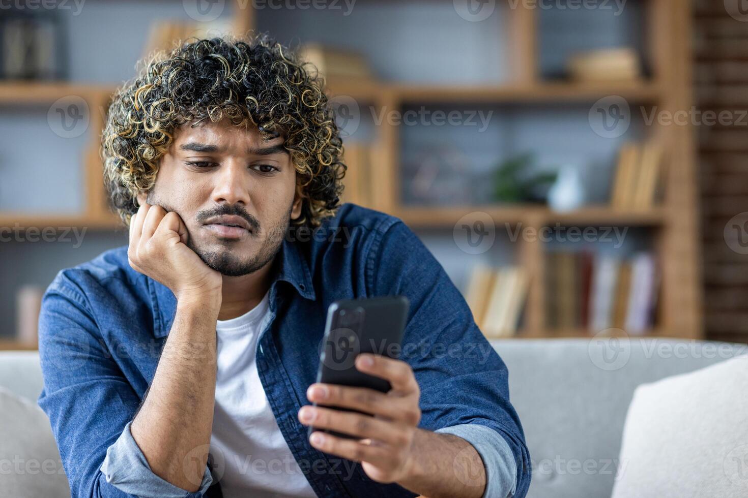 Man looking at smartphone with expression of concern and curiosity on his face photo