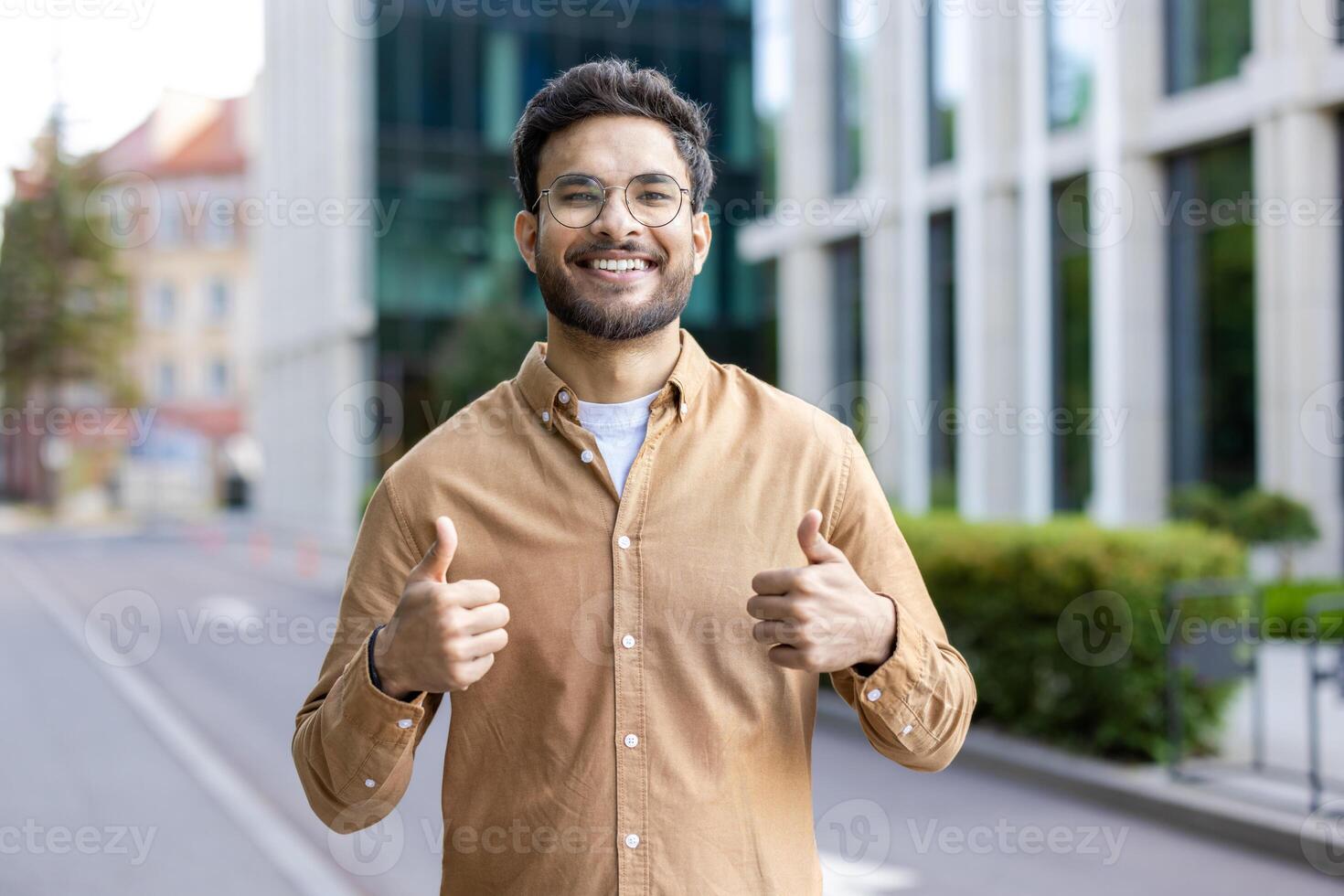 Smiling hispanic man giving thumbs up on city street, expressing positivity and confidence photo