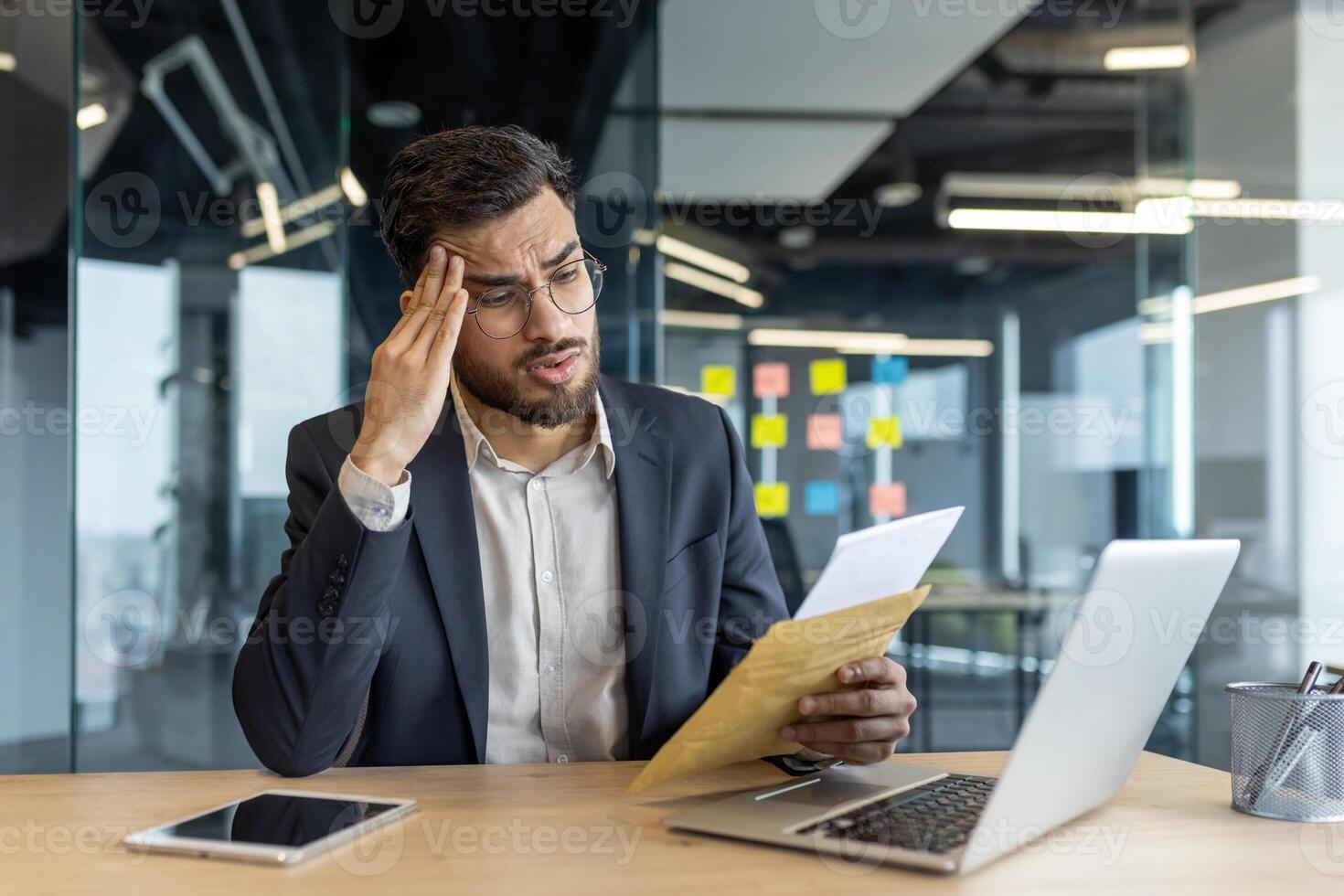 Latin American businessman analyzing documents while seated at a modern office desk photo