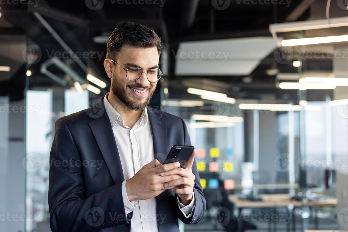 Smiling businessman using smartphone in modern office environment photo