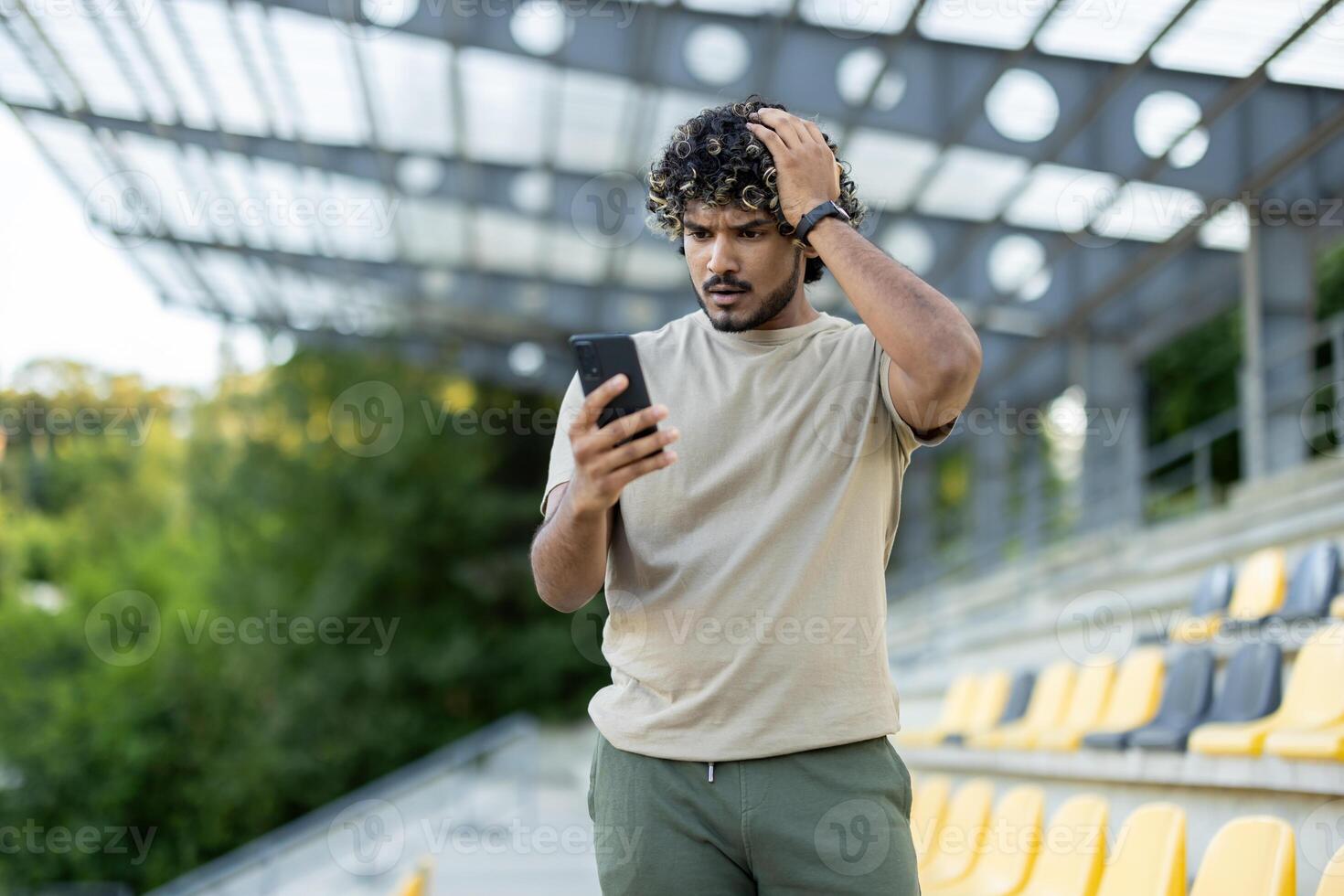 Sad disappointed man with phone in hands walking in park, athlete after fitness and active physical exercise, uses app to track workout progress. photo