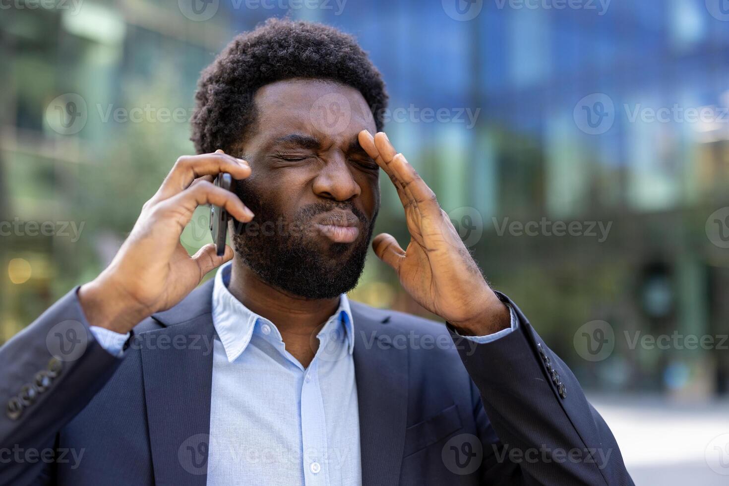 Angry and upset man talking on the phone, businessman walking close-up outside office building. African American man in business suit unhappy with phone conversation. photo