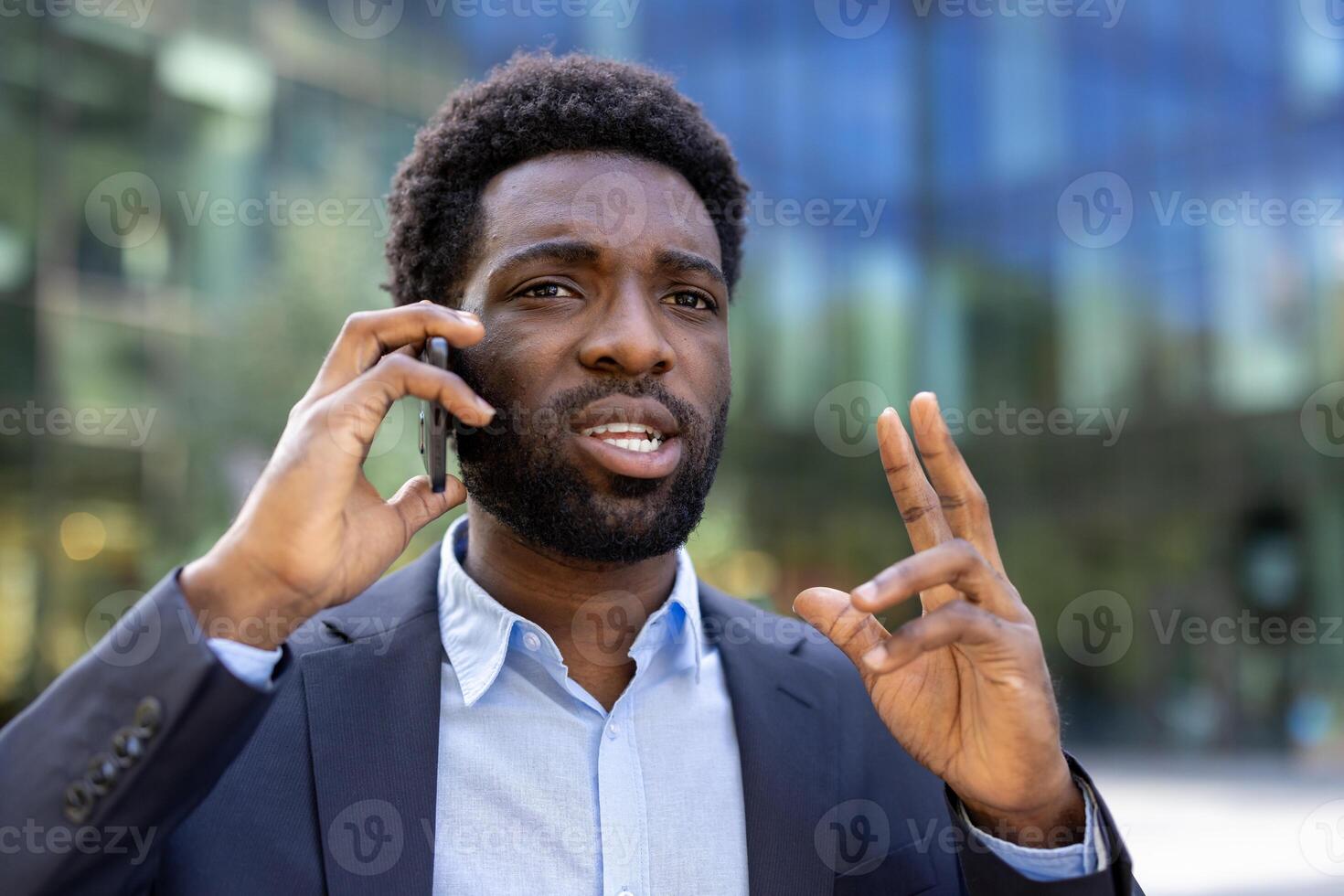 Serious worried man talking on mobile phone. Afro American man close up outside office building, walking and having business conversation. photo