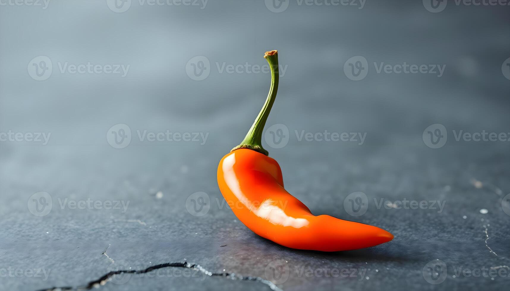 a single orange pepper sitting on top of a table photo
