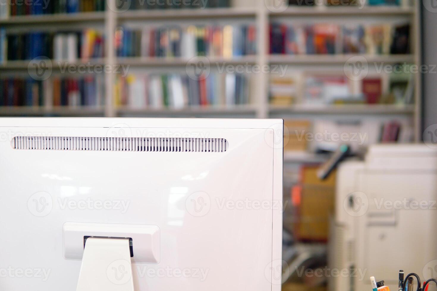 Close-up of a white computer monitor in a library with bookshelf in the background photo
