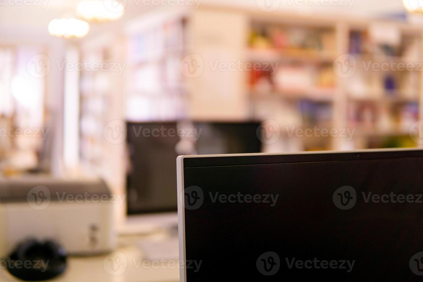Blurred background of traditional library with computer monitor on a foreground and bookshelfs photo