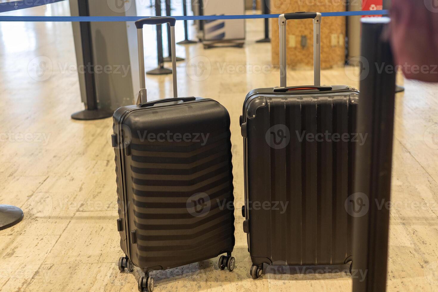 Two black suitcases waiting in an airport check-in line during the morning rush hour photo