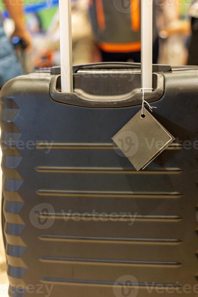 Black suitcase with a tag at a busy airport during the travel rush in the morning hours photo