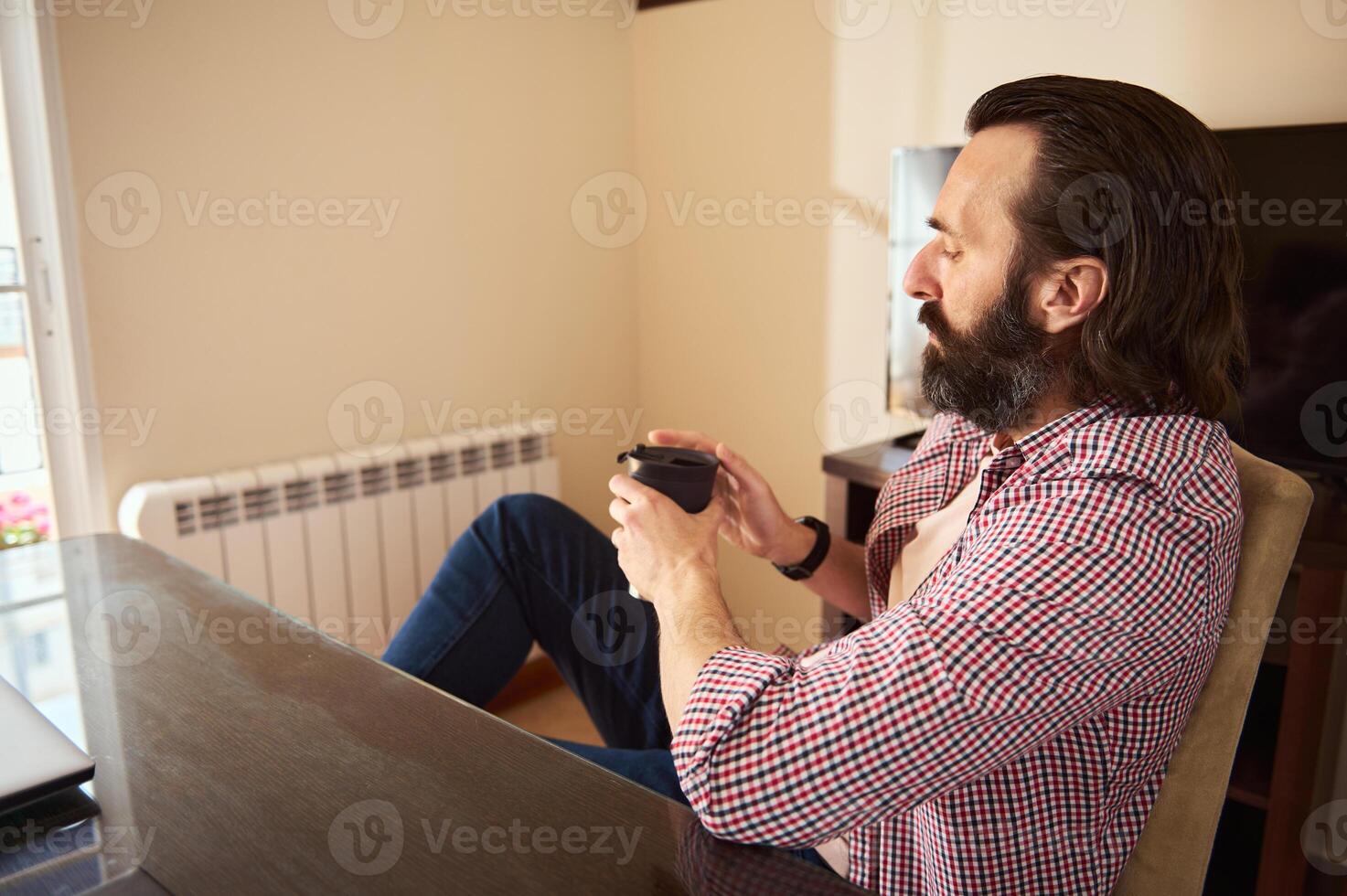 Man Sitting Relaxed at Desk Drinking Coffee in a Modern Home Office photo
