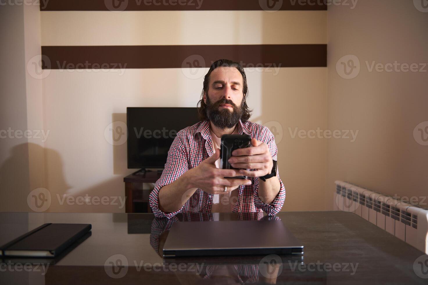 Young Man Using Smartphone at Desk in a Modern Home Office photo