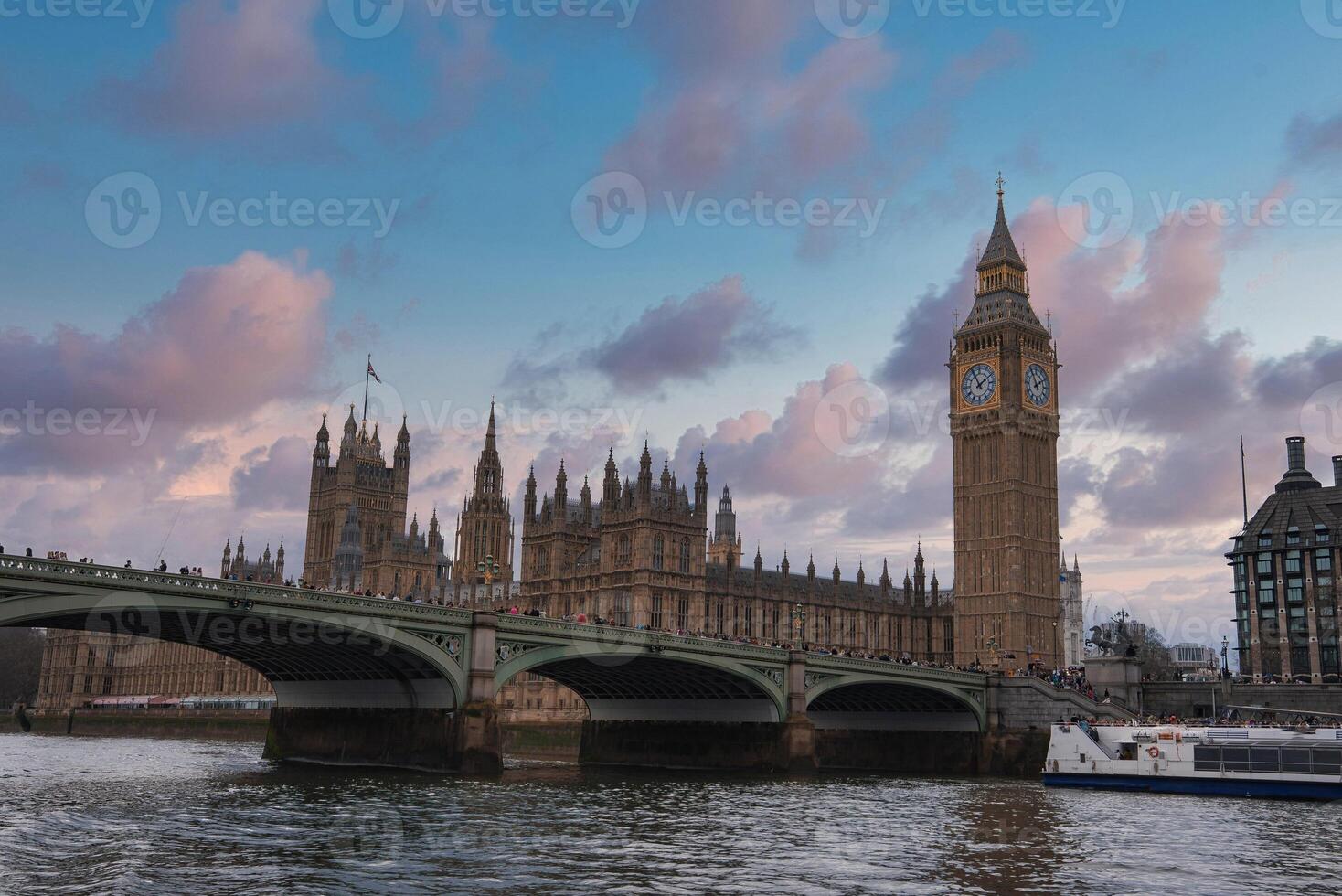 The Palace of Westminster and Elizabeth Tower, with Westminster Bridge over the River Thames, set against a pink and blue evening sky in London. photo